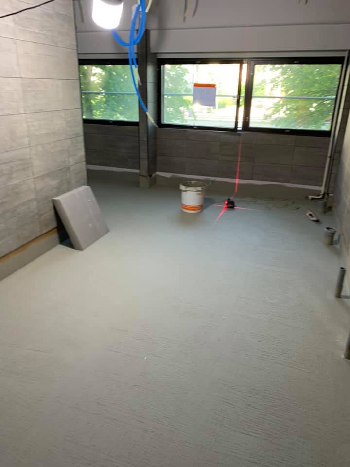 Huoneessa on harmaat laatat seinillä ja lattialla, ikkunat, valo ja työkalut.