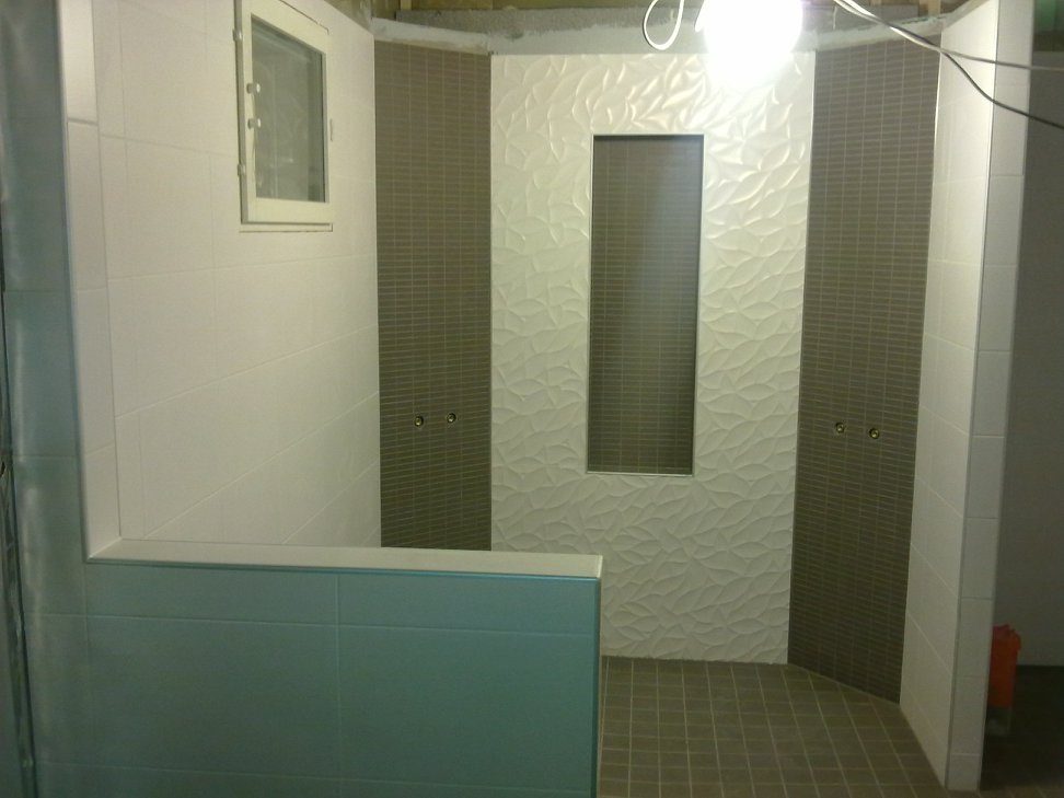 Kylpyhuoneen sisustus, jossa on valkoisia ja harmaita laattoja, ikkuna ja kirkas valo.