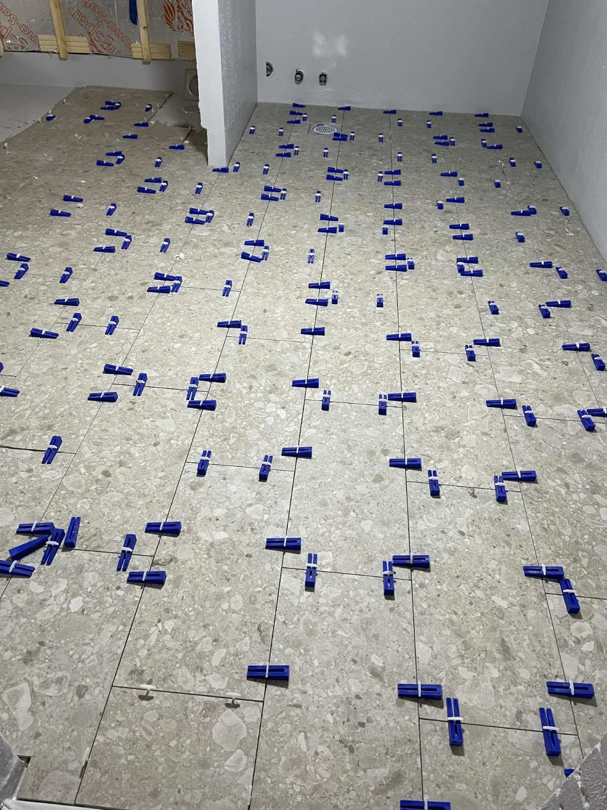 Lattialaatat asennettuna sinisillä kiiloilla, tasainen valaistus.