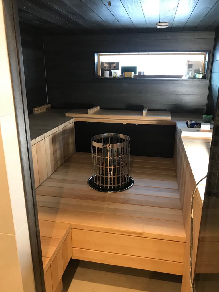 Saunan sisätila, jossa on puinen sisustus, metallinen kiuas ja ikkuna.