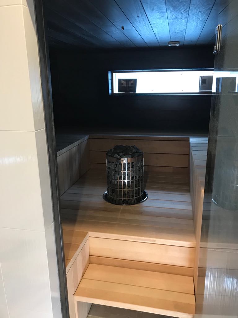 Saunan sisätila, jossa on puupenkit, kivikiuas ja pieni ikkuna.